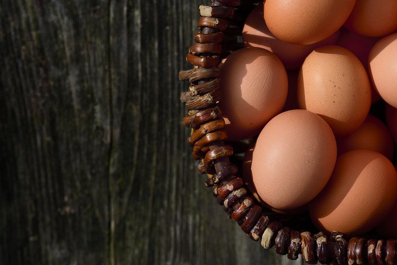 Eggs in basket in front of dark wood by Ulrike Leone