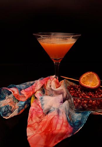 Cocktail met passievruchtensap, sinaasappellikeur, cranberrysap, wodka en verse passievrucht.