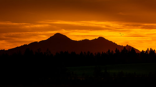 Bergsilhouetten im orangefarbenen Abendlicht bei Schwangau