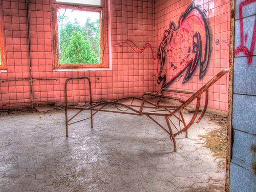 Chambre rose avec cadre rouillé d'une chaise longue dans un vieux sanatorium abandonné