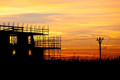 Zonsondergang bij de treinbaan met een silhouette gebouw in aanbouw