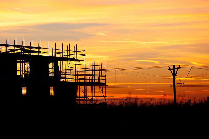 Coucher de soleil à la voie ferrée avec un bâtiment de la silhouette en construction par Dexter Reijsmeijer