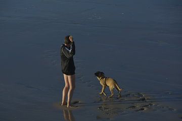 Man with dog on the beach by Taco de Jong