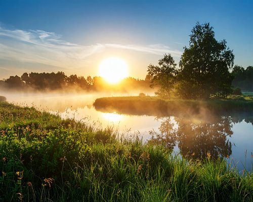 Gouden zonsopgang tussen mist en water