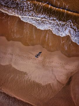 Dronefoto van een fietser op het strand van Nico van Maaswaal