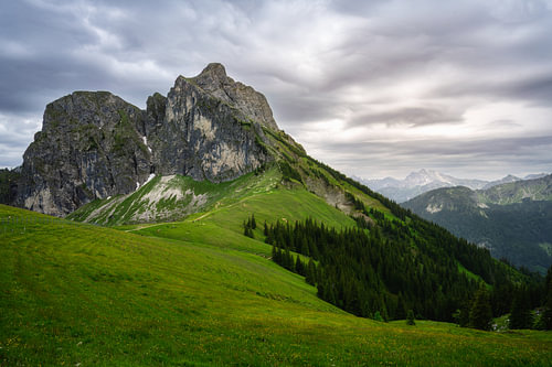 Opvallende top van de Aggenstein boven groene alpenweiden onder de wolken