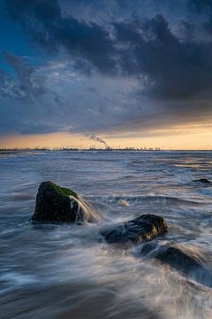 Felsen in der Nordsee mit einem bedrohlichen Himmel und der Industrie in Europoort im Hintergrund von gaps photography