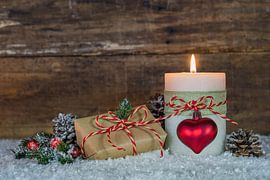 Christmas composition with burning candle and gift box on snow by Alex Winter