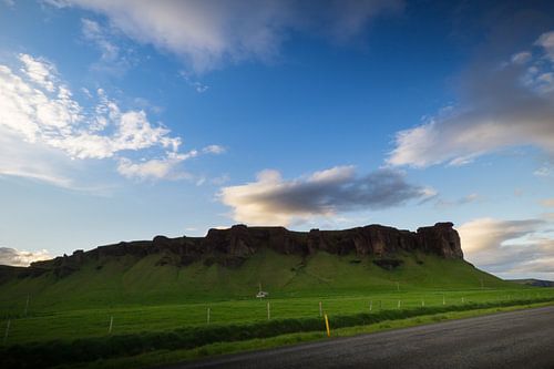 IJsland - Blauwe lucht boven groene weide en vulkanische rotsen bij zonsopgang