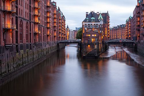 La Speicherstadt de Hambourg et son château entouré d'eau. Les lumières brillent dans le crépuscule.