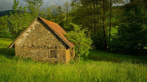 Oud stenen huis op een groene weide in warm licht