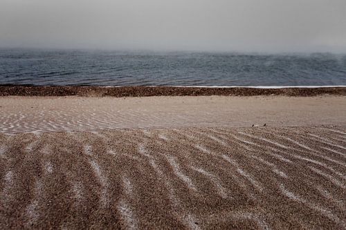 Sombere driekleurige zandige besneeuwde oever van het Baikalmeer