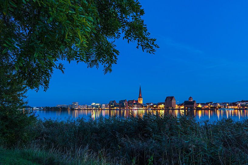 Uitzicht over de Warnow naar de Hanzestad Rostock bij avond van Rico Ködder