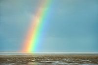 Wolken en regenboog boven Waddenzee bij Westhoek tijdens laag water
