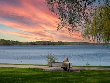 Sonnenuntergang an einem See in der Mecklenburgischen Seenplatte mit einem alten Mann auf einer Bank von Animaflora PicsStock