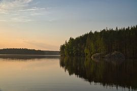 Goldener Sonnenuntergang über einem ruhigen Waldsee in Skandinavien.