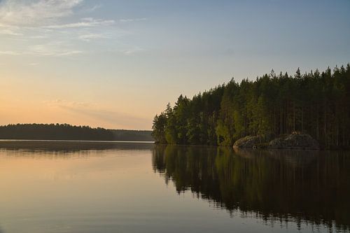 Gouden zonsondergang boven een rustig bosmeer in Scandinavië.