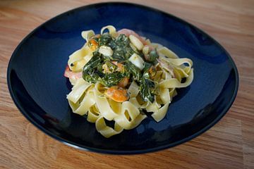 Fettuccini mit Spinat-Käse-Sahnesauce und Meeresfrüchten auf einem Teller angerichtet