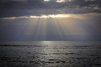 Strand met zee en dreigende lucht met zonnestralen van zonsondergang op Kreta, Griekenland