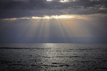 Beach with sea and threatening sky with sunbeams from sunset on Crete, Greece