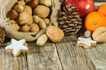 Christmas food composition of nuts in santa claus sack, star shape cookies and fruits by Alex Winter