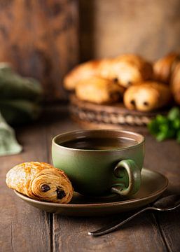Grüne Tasse Tee mit Mini-Schokoladenbrötchen von Iryna Melnyk