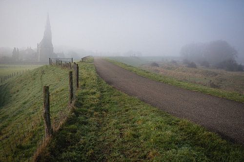 Misty dyke road with church in Dutch landscape