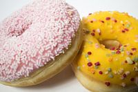 Closeup van geglazuurde donuts met een witte achtergrond.