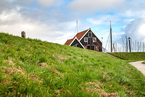 Hoher Seedeich mit traditionellem Fischerhäuschen am Hafen