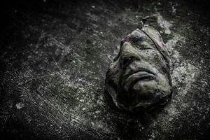 Een oud gebroken masker op een houten tafel van Steven Dijkshoorn