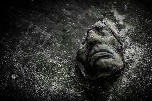 Een oud gebroken masker op een houten tafel