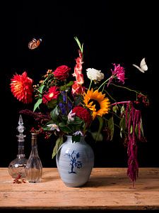 Uitbundig bloemstilleven met antieke karaffen en vlinders