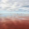 Des gens minuscules sur une plage tranquille avec un ciel flou sur Dirk Wüstenhagen