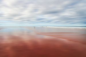 Winzige Menschen an einem ruhigen Strand mit verschwommenem Himmel