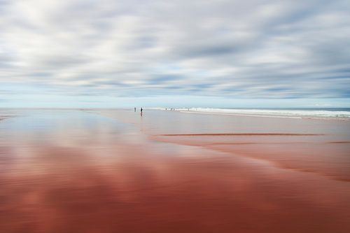 Winzige Menschen an einem ruhigen Strand mit verschwommenem Himmel von Dirk Wüstenhagen