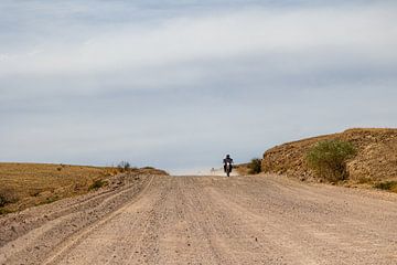 Motorradfahrer auf Schotterstraße.