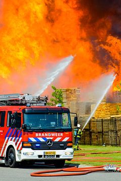 Fire engine in front of a fire in an industrial area by Sjoerd van der Wal