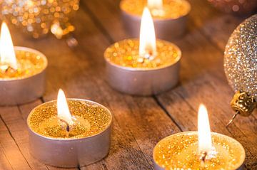 Festlich brennende goldene Advents- und Weihnachtskerzen mit glitzernden Kugeln von Alex Winter