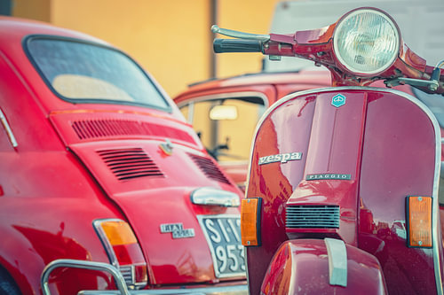 Oldtimer rode Fiat 500 en een oldtimer rode Vespa scooter in Italië.