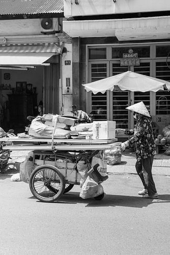 Man loopt over straat in Ho Chi Minh City met karakteristieke vietnamese hoed