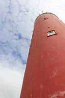 Phare rouge avec un ciel bleu légèrement nuageux