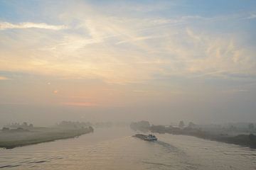 Binnenvaartschip op de rivier de IJssel tijdens zonsopkomst