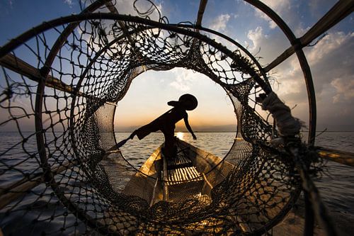 Fisherman with traditional boat on Inle Lake in Myanmar tries the old-fashioned way to catch a fish 