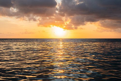 Zonsondergang met een kalme zee en een weerspiegeling van de zon in het water