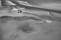 Plane above the Waddensea in black and white