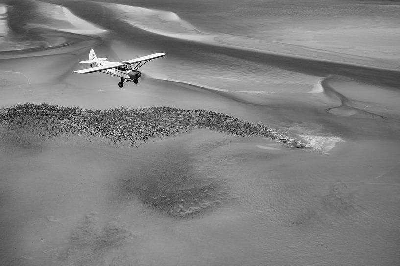 Vliegtuig boven de Waddenzee in zwart-wit van Planeblogger