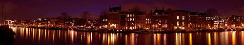 Panorama van een stadsgezicht van Amsterdam bij nacht aan de rivier de Amstel in Nederland