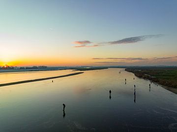 Schaatsen op een meer tijdens een prachtige winterse zonsondergang van Sjoerd van der Wal Fotografie