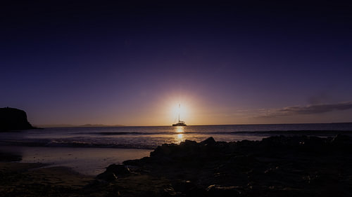 Zeilboot bij zonsondergang – Panorama van de baai van Papagallo op Lanzarote met rotskust aan zee