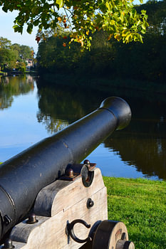 Vue du canal à Dokkum, en Frise (Hardridersgracht / Grootdiep / Dokkumergrootdiep), avec un canon antique au premier plan, et des arbres se reflétant dans l'eau à l'arrière-plan.
